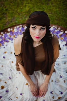 Pretty brunette woman sitting on the floor with a flowered skirt. View from above