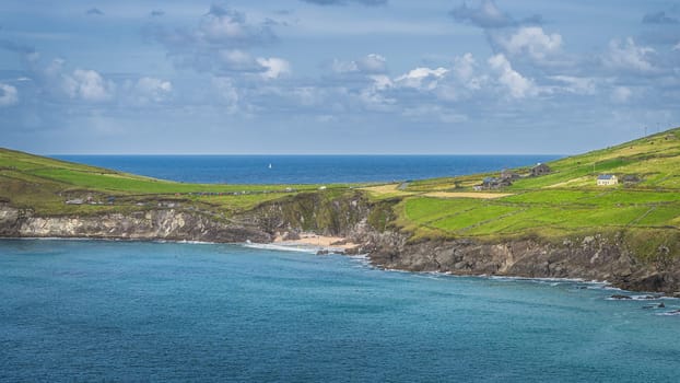 Tourist swimming in the see and relaxing on small hidden Coumeenoole Beach between cliffs in Dingle Peninsula, Wild Atlantic Way, Kerry, Ireland