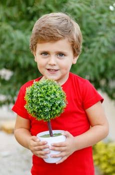Happy child with a small tree in the garden