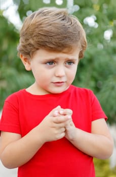Sad child with red t-shirt in the garden