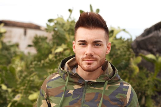 Attractive guy with military jacket and plants background