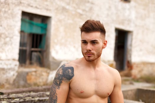 Attractive guy showing his muscles in a old house