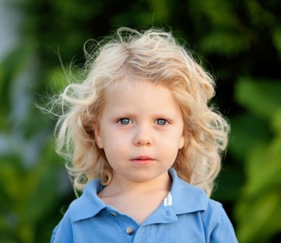 Beautiful boy three year old with long blond hair in the park
