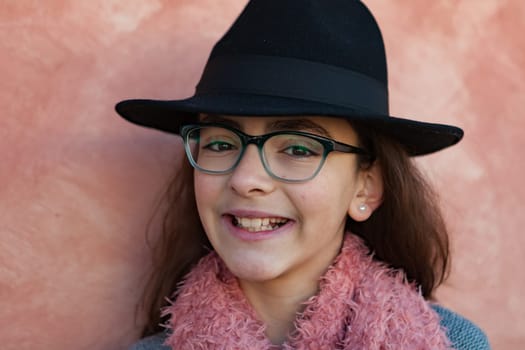 Smiling preteen girl wearing pink scarf and a black hat