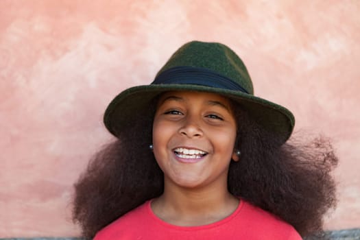 Pretty girl with long afro hair in the garden with a elegant black hat