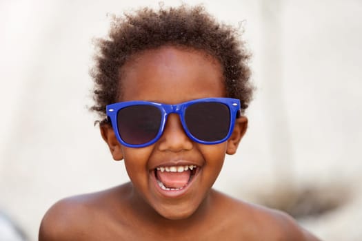 Funny Afro-American kid with blue sunglasses and a beautiful smile