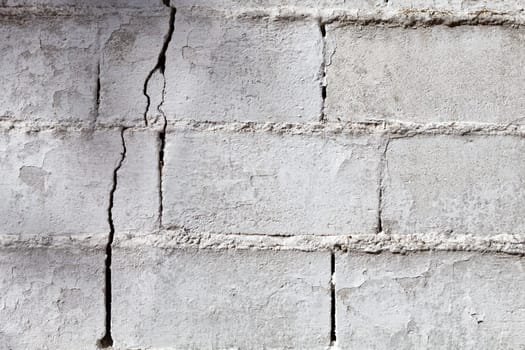 Crack in a white wall with cement brick surface