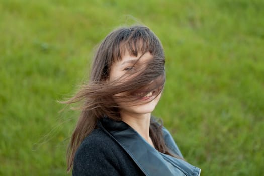 Outdoor portrait of beautiful happy girl laughing while the wind moves her hair