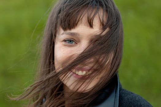 Outdoor portrait of beautiful happy girl laughing while the wind moves her hair