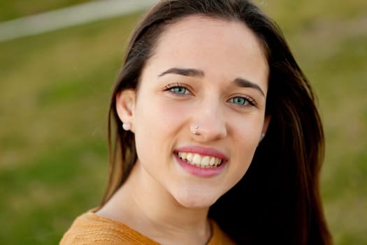 Outdoor portrait of beautiful happy teenager girl laughing with perfect teeth in field