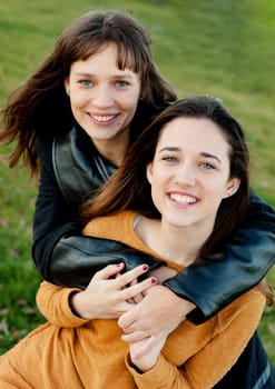 Outdoor portrait of two happy sisters relaxed in a park