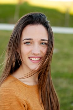 Outdoor portrait of beautiful happy teenager girl laughing with perfect teeth in field