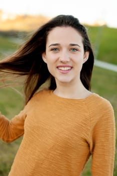 Outdoor portrait of beautiful happy teenager girl laughing while the wind moves her hair