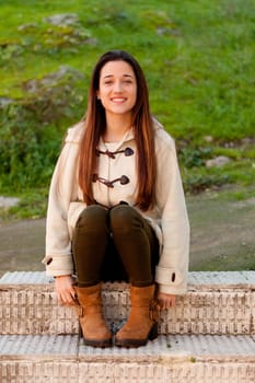 Pretty teenager girl sitting on the sidewalk in a park