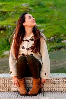 Pretty teenager girl sitting on the sidewalk in a park
