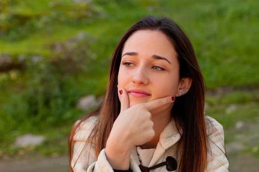 Smiling teen girl thinking outside with a natural green of background