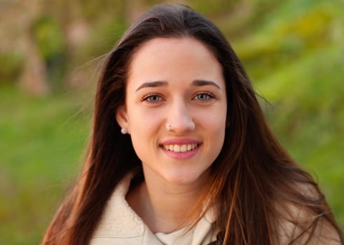 Smiling teen girl outside with a natural green of background