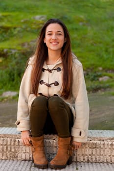 Pretty teenager girl sitting on the sidewalk in a park