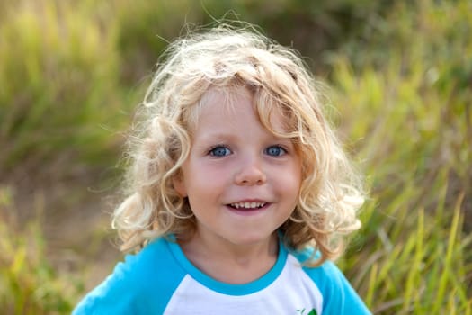 Small child with long blond hair enjoying of a sunny day