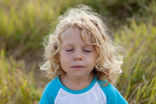 Small child with long blond hair enjoying of a sunny day