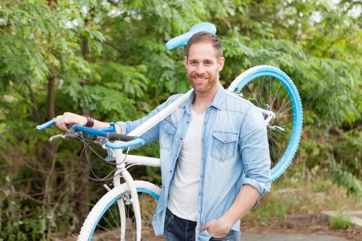 Handsome man with denim clothes enjoying with his bike in the park