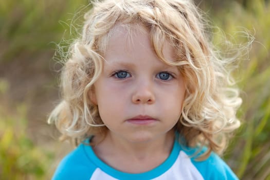 Small child with long blond hair enjoying of a sunny day
