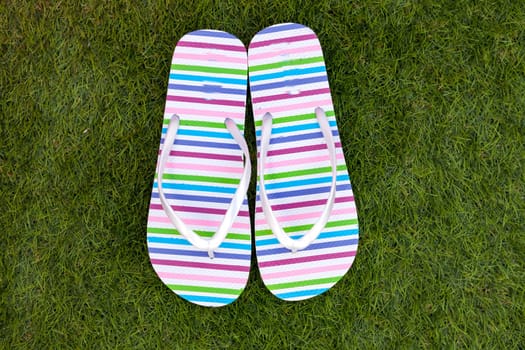 Flip-flops on the green grass of the pool