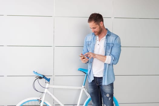 Casual guy next to a vintage bicycle with the mobile wearing denim shirt