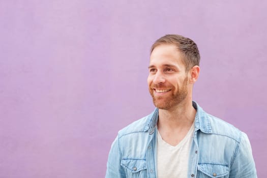 Attractive casual man with denim shirt on a purple background
