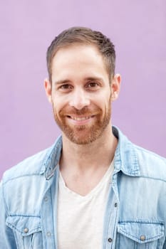Attractive casual man with denim shirt on a purple background