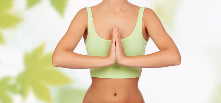 Anonymous woman doing yoga with green leaves of background