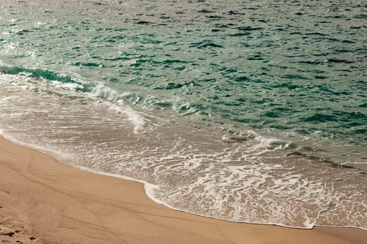 Foamed blue waves breaking in the beach
