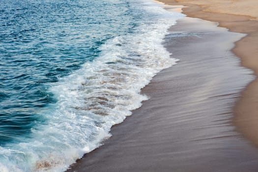 Foamed blue waves breaking in the beach