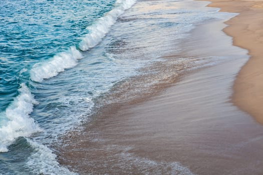 Foamed blue waves breaking in the beach