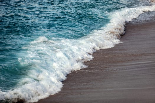 Foamed blue waves breaking in the beach