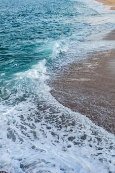 Foamed blue waves breaking in the beach