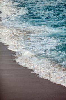 Foamed blue waves breaking in the beach