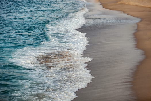 Foamed blue waves breaking in the beach