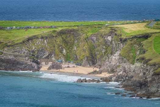 Tourist swimming in the see and relaxing on small hidden Coumeenoole Beach between cliffs in Dingle Peninsula, Wild Atlantic Way, Kerry, Ireland