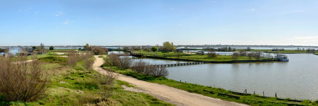 dirt road and lagoon view from watchtower, shot in bright spring sun light at Comacchio, Ferrara,  Italy.
