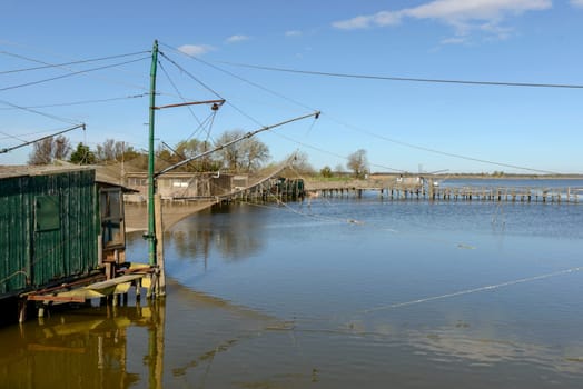 fishnet of old traditional stilt fishing hut on the lagoon, shot in bright spring sun light at Comacchio, Ferrara,  Italy.