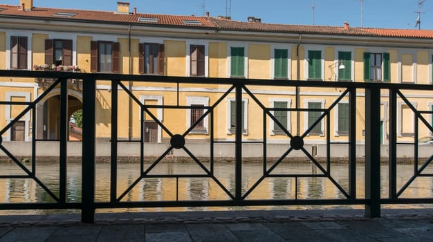 view of ancient traditional houses on embankment of artificial historic canal  in foresight iron railing, shot in summer bright light.