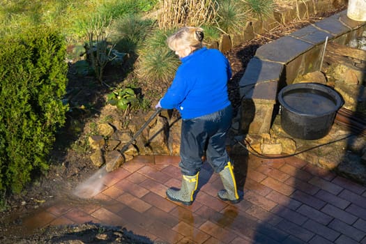 Worker cleaning driveway with gasoline high pressure washer splashing the dirt,professional cleaning services.High pressure cleaning,lower body.