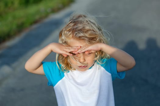 Little boy covering his eyes by the sun, on a sunny day
