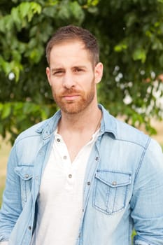 Casual guy with a denim shirt relaxed in a park