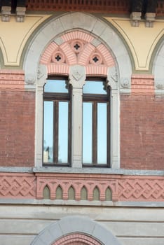 decorated twin window at historical factory in old industrial village, shot in winter at Crespi Adda, Capriate, Lombardy, Italy.