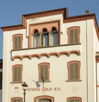 decorated facade of public primary school in old industrial village, shot in winter at Crespi Adda, Capriate, Lombardy, Italy.