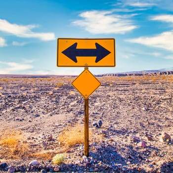 Directional sign in the desert with scenic blue sky and wide horizon. Concept for trip, freedom, holiday and transportation.