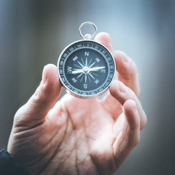Man on an adventure is holding a compass in his hand for finding is route