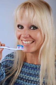 Young blonde woman brushing her teeth